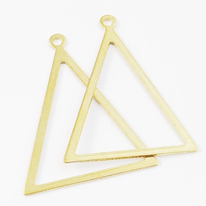 Puede incluir: Dos abalorios de metal de forma triangular dorada con un bucle en la parte superior para sujetar a joyas u otras manualidades.