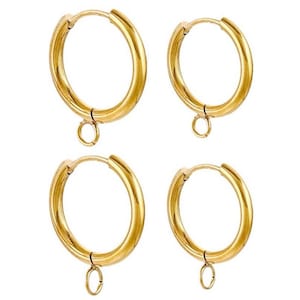 May include: A pair of gold-toned hoop earrings with a small dangle charm. The earrings are made of metal and have a polished finish.