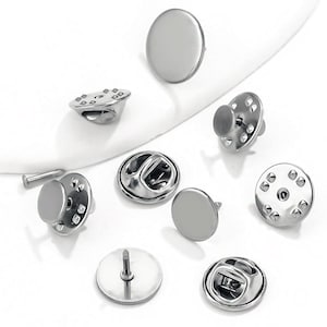 Puede incluir: Un conjunto de respaldos de alfiler de metal plateado para sujetar insignias, broches u otros accesorios a la ropa. Los respaldos de alfiler vienen en una variedad de estilos, incluyendo redondos, cuadrados y rectangulares.