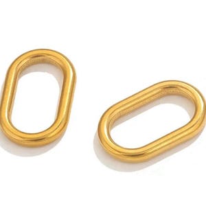 Könnte beinhalten: Zwei goldfarbene, ovale Metallringe mit einer glatten, polierten Oberfläche. Jeder Ring weist ein durchgehendes, abgerundetes Schlaufendesign mit einer hohlen Mitte auf und dient als Einzelkomponente für Schmuckherstellung oder Bastelprojekte.