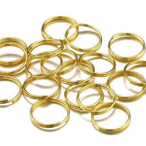 Pu&ograve; includere: Un mucchio di 15 portachiavi in metallo dorato. I portachiavi sono tutti della stessa dimensione e forma, e sono disposti in modo casuale.