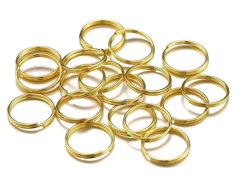 Pu&ograve; includere: Un mucchio di 15 portachiavi in metallo dorato. I portachiavi sono tutti della stessa dimensione e forma, e sono disposti in modo casuale.