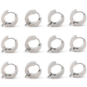 May include: Twelve silver hoop earrings with a hinged clasp. The earrings are all the same size and shape.
