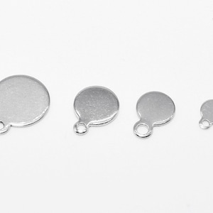 以下が含まれることがあります： 上部に小さなループが付いた、銀色の丸い金属製のチャームが4つ。チャームはサイズが異なり、最も大きいものは直径約2.5cmです。