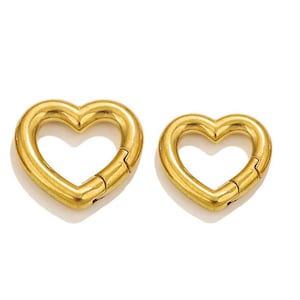May include: Two gold heart-shaped clasps, one larger than the other. The clasps are made of metal and have a smooth, shiny finish.