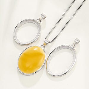 Puede incluir: Un collar de cadena de plata con tres colgantes ovalados. Dos de los colgantes est&aacute;n vac&iacute;os y un colgante presenta una piedra ovalada amarilla.