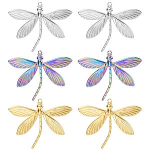 Op de afbeelding: Zes libellenbedels in drie verschillende afwerkingen: zilver, regenboogkleurig en goud. Elke bedel heeft een lus aan de bovenkant om aan sieraden of andere knutselprojecten te bevestigen.