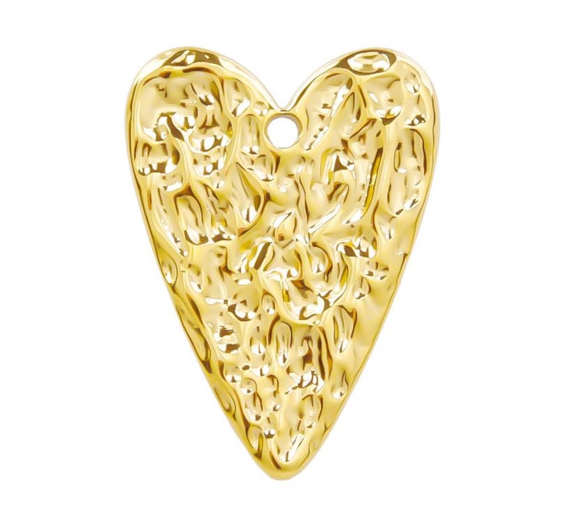 May include: A gold-colored heart-shaped pendant with a textured surface. The pendant has a hole at the top for attaching a chain or cord.