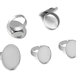 May include: Five silver-toned rings with oval-shaped bezels. The bezels are designed to hold a cabochon or other flat-backed embellishment.