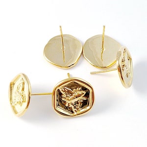 Puede incluir: Cuatro pendientes de tono dorado con un diseño hexagonal que presenta un motivo de abeja. Los pendientes tienen un cierre de poste.