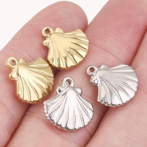 Puede incluir: Cuatro abalorios de concha marina en oro y plata. Los abalorios tienen forma de concha de vieira. Los abalorios son perfectos para la elaboración de joyas o para añadir un toque de fantasía a cualquier proyecto artesanal.