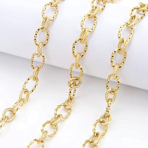 May include: Close-up of three strands of gold-colored chain. The chains have an oval link design with a textured, twisted rope pattern. The chains are displayed against a white background.