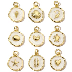 Puede incluir: Nueve dijes de oro con esmalte blanco, cada uno con un diseño diferente de temática marina: una concha, una estrella de mar, un corazón, un delfín, una tortuga, una almeja, una vieira, una ola y una concha con una perla.