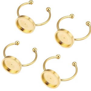 Op de afbeelding: Vier gouden metalen ringblanken met ronde, platte, bezel-gezet bases. De bases zijn ontworpen om een cabochon of andere platte versiering te bevatten.