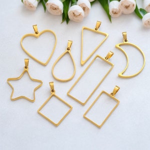 Puede incluir: Un conjunto de nueve colgantes de metal dorado en diferentes formas, incluyendo un corazón, una lágrima, una luna creciente, una estrella, un triángulo y tres rectángulos. Los colgantes miden aproximadamente 5 cm y tienen un acabado liso y pulido.