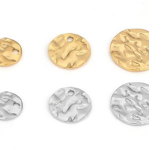 Könnte beinhalten: Sechs gehämmerten Metall-Scheibenanhänger in Gold- und Silbertönen. Die Anhänger sind rund mit strukturierter Oberfläche und einem Loch zum Auffädeln. Die Größen variieren, mit drei goldenen und drei silbernen Scheiben.