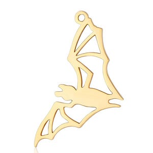 May include: Gold-coloured metal charm shaped like a bat with a cutout design.