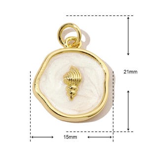 K&ouml;nnte beinhalten: Goldfarbener Anh&auml;nger mit einem wei&szlig;en Emaille-Muschel-Design. Der Anh&auml;nger ist 15 mm breit und 21 mm hoch.
