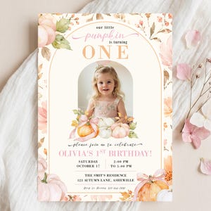 May include: A rectangular birthday invitation card featuring a central arch frame containing a photograph of a child. The design includes watercolor illustrations of pumpkins and autumn leaves in soft peach and cream tones with the text: our little pumpkin is turning ONE, please join us to celebrate OLIVIA'S 1ST BIRTHDAY, SATURDAY OCTOBER 17, 2:00 PM TO 5:00 PM, THE SMIT'S RESIDENCE 123 AUTUMN LANE, ASHEVILLE, Rsvp to thanks 123-456-7890.