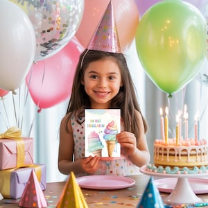 May include: A young girl wearing a party hat holds a birthday card with ice cream cone illustrations. A birthday cake with lit candles sits on a cake stand. Balloons in pink, green, and white are in the background.