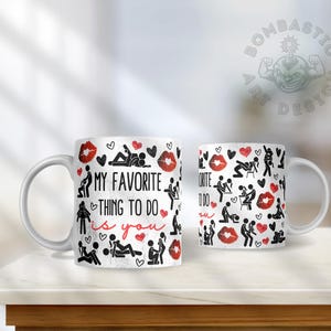 May include: White ceramic coffee mug with a black and red design. The mug features a pattern of stick figures in various poses, hearts, and lips. The text "My favorite thing to do is you" is printed on the mug.