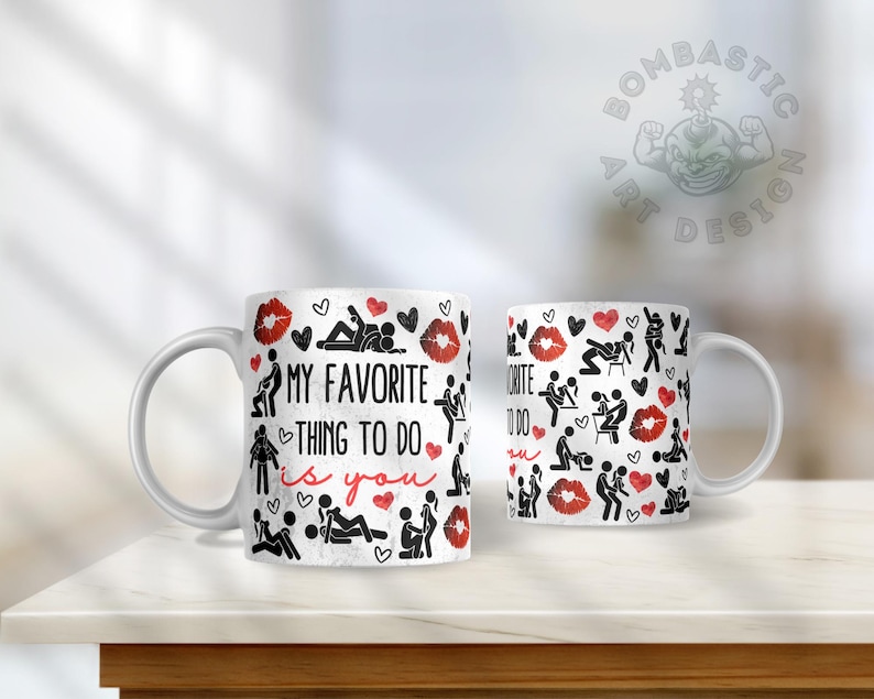 May include: White ceramic coffee mug with a black and red design. The mug features a pattern of stick figures in various poses, hearts, and lips. The text "My favorite thing to do is you" is printed on the mug.
