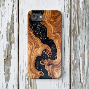 May include: A wooden phone case with a unique design. The case features a dark, star-filled center, framed by swirling, light brown wood grain. The case has a camera cutout and is designed for a smartphone.