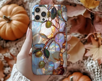 May include: A pearlescent phone case featuring a stained-glass design of an olive branch with green olives and leaves. The case has a mosaic-like pattern with iridescent colors. The background includes pumpkins and autumn leaves.