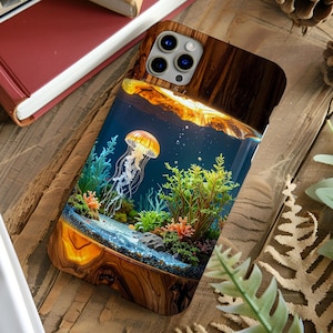 Puede incluir: Funda de teléfono de madera que presenta una detallada escena submarina con una medusa, corales y plantas. La funda tiene un diseño de vetas de madera en la parte superior e inferior, y la imagen está encapsulada en una capa transparente.