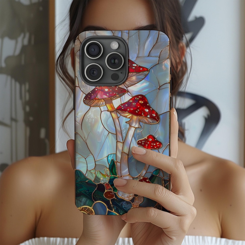 K&ouml;nnte beinhalten: Smartphone-H&uuml;lle mit einem Buntglas-Design mit roten und wei&szlig;en Pilzen vor blau-wei&szlig;em Hintergrund. Die H&uuml;lle hat eine gl&auml;nzende Oberfl&auml;che und einen Schutzsto&szlig;f&auml;nger.