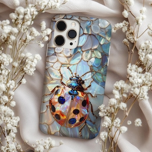 May include: A smartphone case featuring a colorful ladybug design. The case has a mosaic-like background with blue, white, and iridescent accents. The ladybug has a detailed, jewel-toned appearance with black spots and a gold outline.