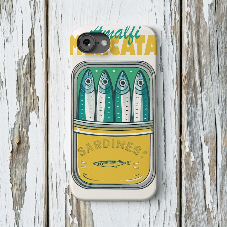 May include: A white phone case featuring a sardine can design. The can is yellow and green, with the word "SARDINES" and a fish illustration. The top of the case has the words "Amalfi" and "Mescata" in green and yellow.