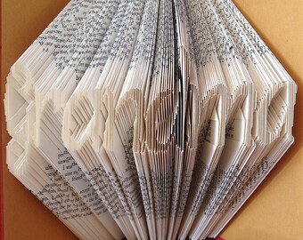 May include: A book folded into the shape of the word "LOVE" with the pages fanned out. The book is bound in a brown cover with a red spine.