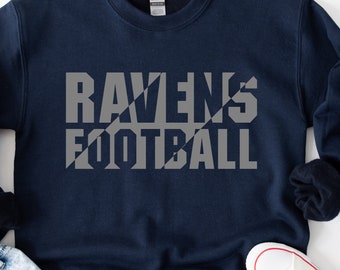 May include: A navy blue sweatshirt with the words "RAVENS FOOTBALL" printed in a grey, diagonal, block font.