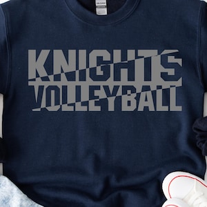 Könnte beinhalten: Marineblaues Sweatshirt mit dem Schriftzug "KNIGHTS VOLLEYBALL" in grauen Blockbuchstaben mit geometrischem Design. Das Sweatshirt hat einen Rundhalsausschnitt.
