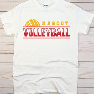 May include: White t-shirt with a red and yellow volleyball graphic and the text "MASCOT VOLLEYBALL".