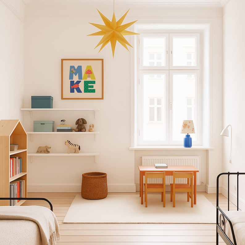 Puede incluir: Una habitaci&oacute;n infantil luminosa con una decoraci&oacute;n en forma de estrella colgada del techo. La habitaci&oacute;n cuenta con una obra de arte enmarcada con la palabra "MAKE", una peque&ntilde;a mesa con dos sillas y una estanter&iacute;a. Estantes exhiben juguetes y cajas de almacenamiento.