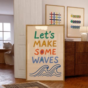 Puede incluir: Una impresi&oacute;n art&iacute;stica enmarcada con las palabras "Let's MAKE SOME WAVES" en letras coloridas, con ilustraciones de olas azules. Otras dos impresiones enmarcadas presentan dise&ntilde;os geom&eacute;tricos y de orugas coloridas. Las impresiones est&aacute;n en una habitaci&oacute;n con piso de madera.