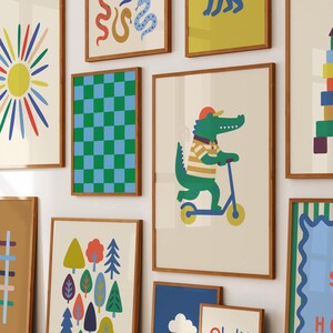 Puede incluir: Una colecci&oacute;n de l&aacute;minas art&iacute;sticas enmarcadas con ilustraciones coloridas. Una l&aacute;mina muestra un caim&aacute;n verde montado en un patinete azul. Otras l&aacute;minas incluyen un sol, un patr&oacute;n de tablero de ajedrez y &aacute;rboles. Los marcos son de color marr&oacute;n c&aacute;lido.