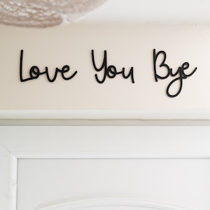Letrero de madera con la frase "Te quiero, adiós" para entrada o pasillo. Letras pintadas de negro.