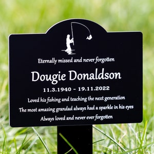 May include: Black metal memorial plaque with a silhouette of a person fishing. The plaque reads "Eternally missed and never forgotten Dougie Donaldson 11.3.1940 - 19.11.2022 Loved his fishing and teaching the next generation The most amazing grandad always had a sparkle in his eyes Always loved and never ever forgotten".