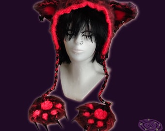 Puede incluir: Un gorro con capucha rojo y negro con protuberancias en forma de orejas y mitones a juego con forma de pata. El gorro y los mitones tienen una textura peluda con detalles en rojo. Los mitones presentan púas negras en forma de garra.