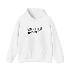May include: White hooded sweatshirt with a front pocket and drawstring. The front features the text "Esto es una BUUURLA" in black, with a small flag graphic. A casual, comfortable garment.
