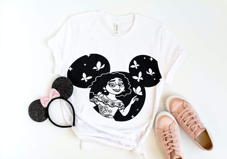 May include: White t-shirt with a black and white graphic of a girl with butterflies in a Mickey Mouse silhouette.