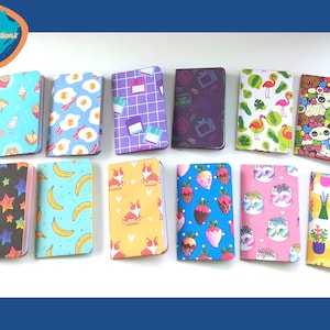 May include: Twelve small notebooks with different colorful patterns. The patterns include: ice cream cones, eggs, grid, TV, flamingos, pandas, stars, bananas, corgis, strawberries, cats, and plants.