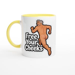 Puede incluir: Una taza de cerámica blanca con asa y borde interior de color amarillo brillante. La taza presenta una ilustración gráfica de una persona corriendo desnuda, acompañada por el texto negro en negrita que dice Free Your Cheeks en una fuente estilizada.