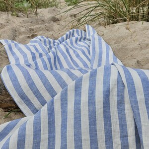 Blue and white striped linen beach towel on sandy dunes, lightweight 100% linen with a soft natural texture.