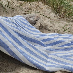 Blue and white striped linen beach towel on sandy dunes, lightweight 100% linen with a soft natural texture.