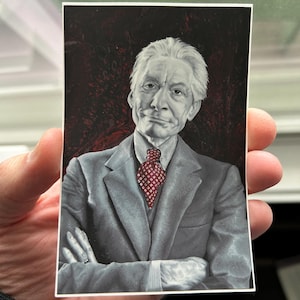 May include: A black and white portrait of a man with white hair and a red patterned tie. The man is wearing a gray suit jacket and has a serious expression on his face.
