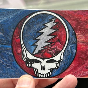 May include: A sticker with a psychedelic Grateful Dead Steal Your Face logo on a blue and red marbled background.